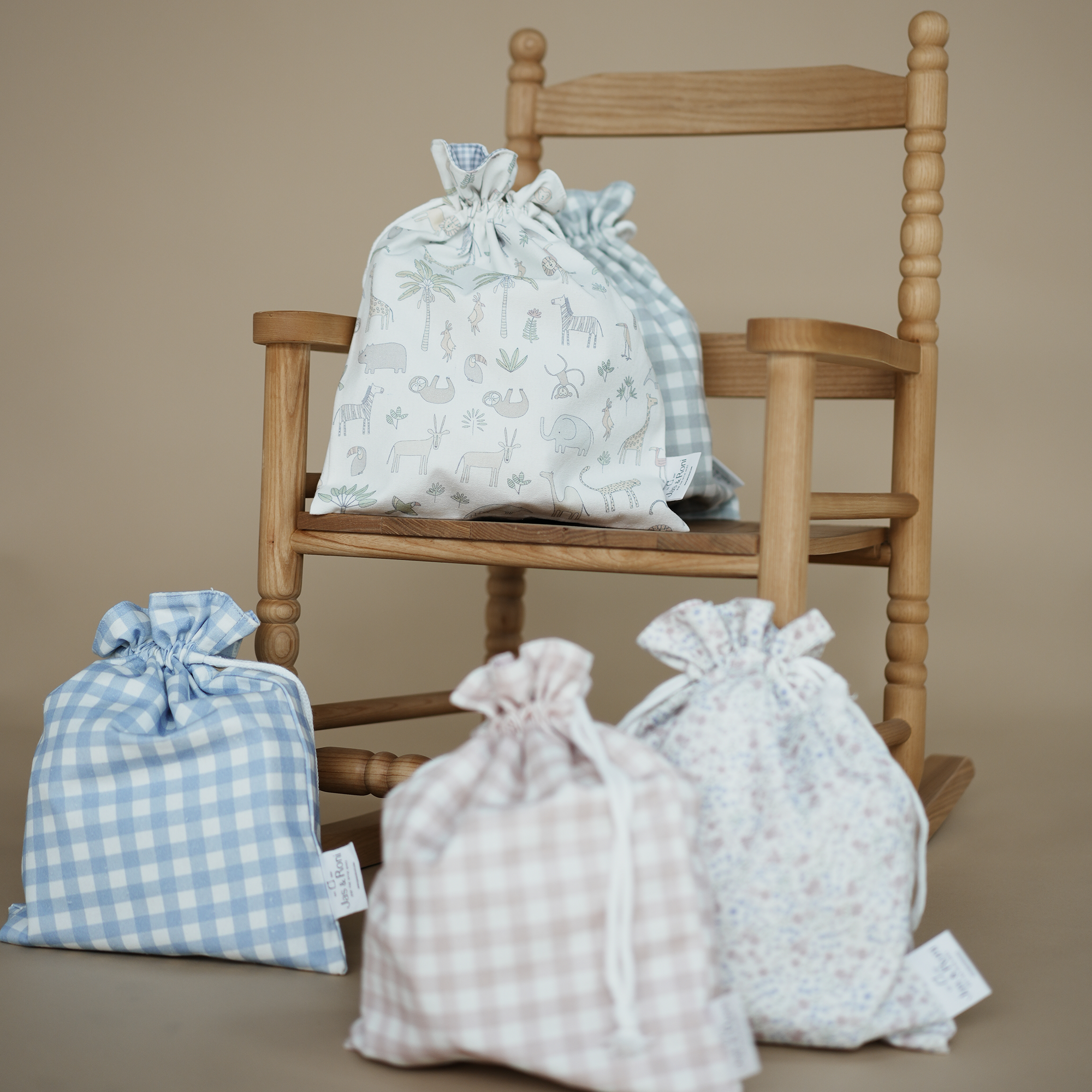 Set de 4 bolsitas con jareta en diferentes estampados sobre una sila de madera fondo beige