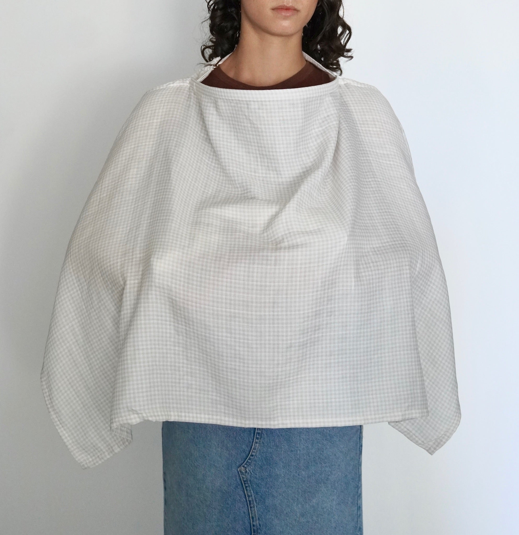 Mujer cubierta con una manta de lactancia a cuadros beige