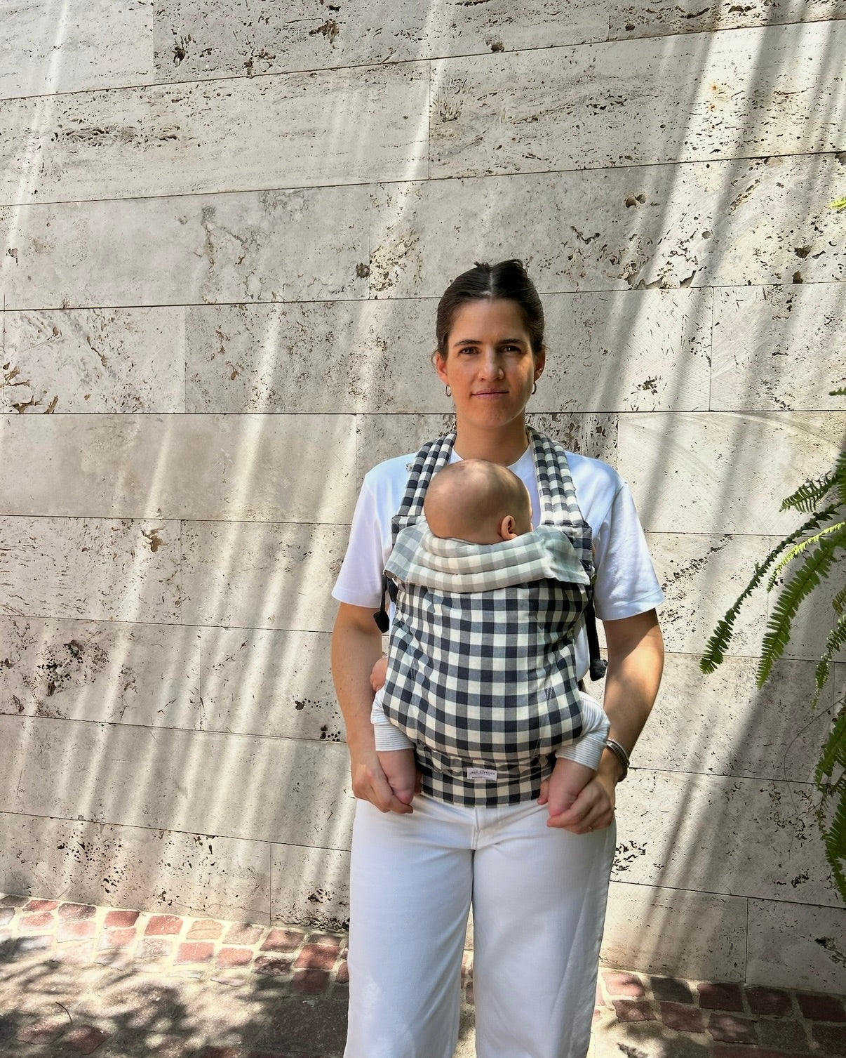 Mama con bebé en canguro para bebé con pared de fondo