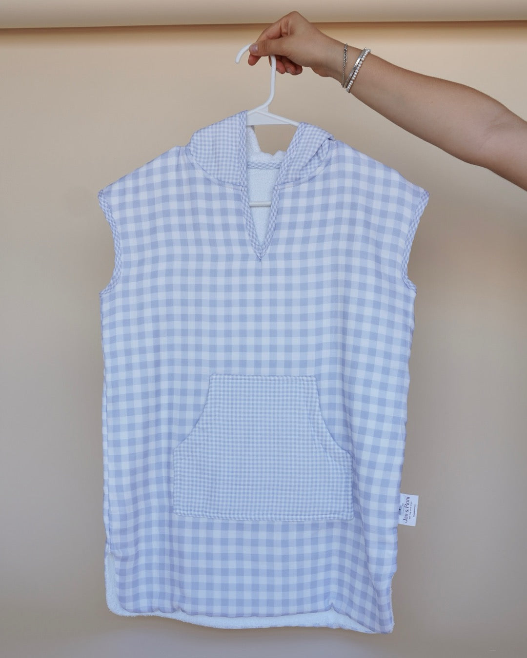 Poncho de toalla y muselina en gancho sostenido por una mano estampado en  cuadros azules