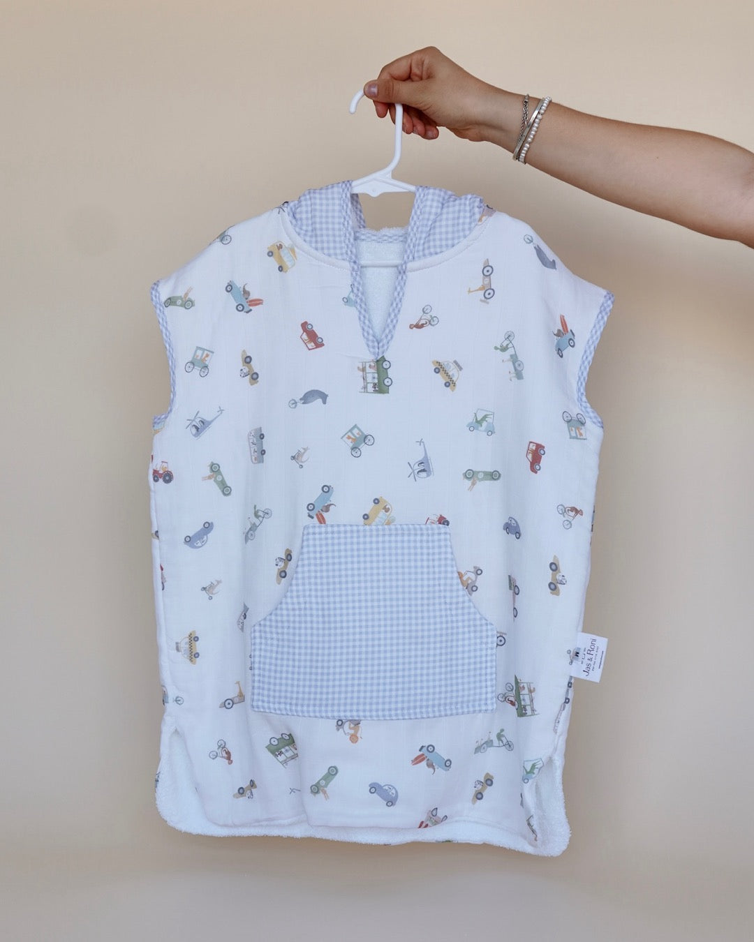 Poncho de toalla y muselina en gancho sostenido por una mano estampado en  carritos