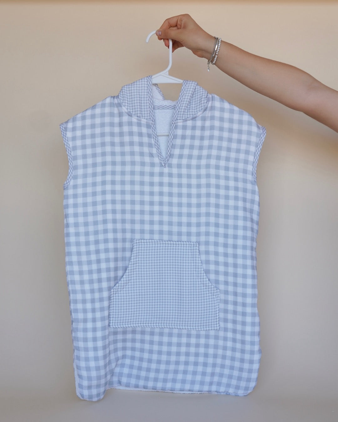 Poncho de toalla y muselina en gancho sostenido por una mano estampado en  cuadros grises