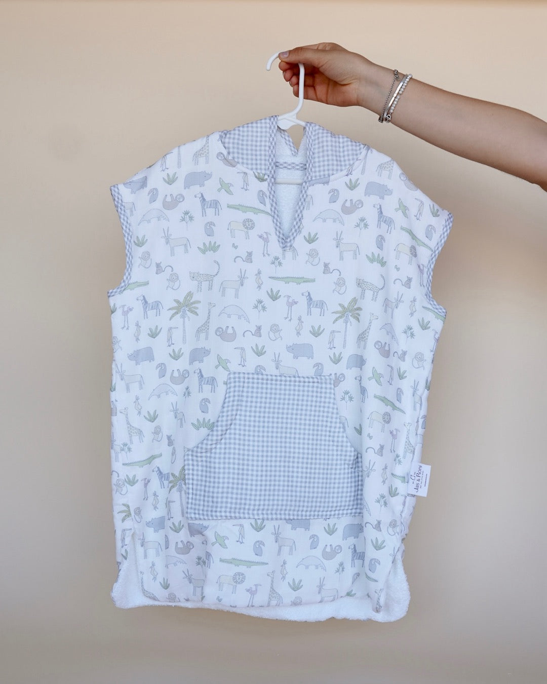 Poncho de toalla y muselina en gancho sostenido por una mano estampado en safari