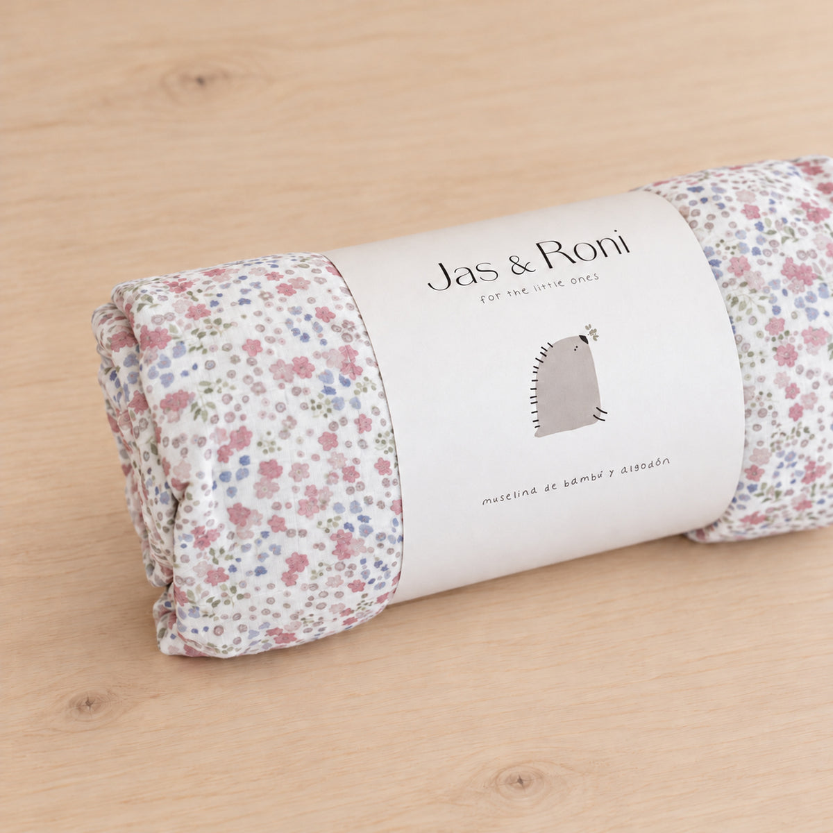 Edredón de muselina little flowers & pink squares — detalle enrollado sobre madera clara