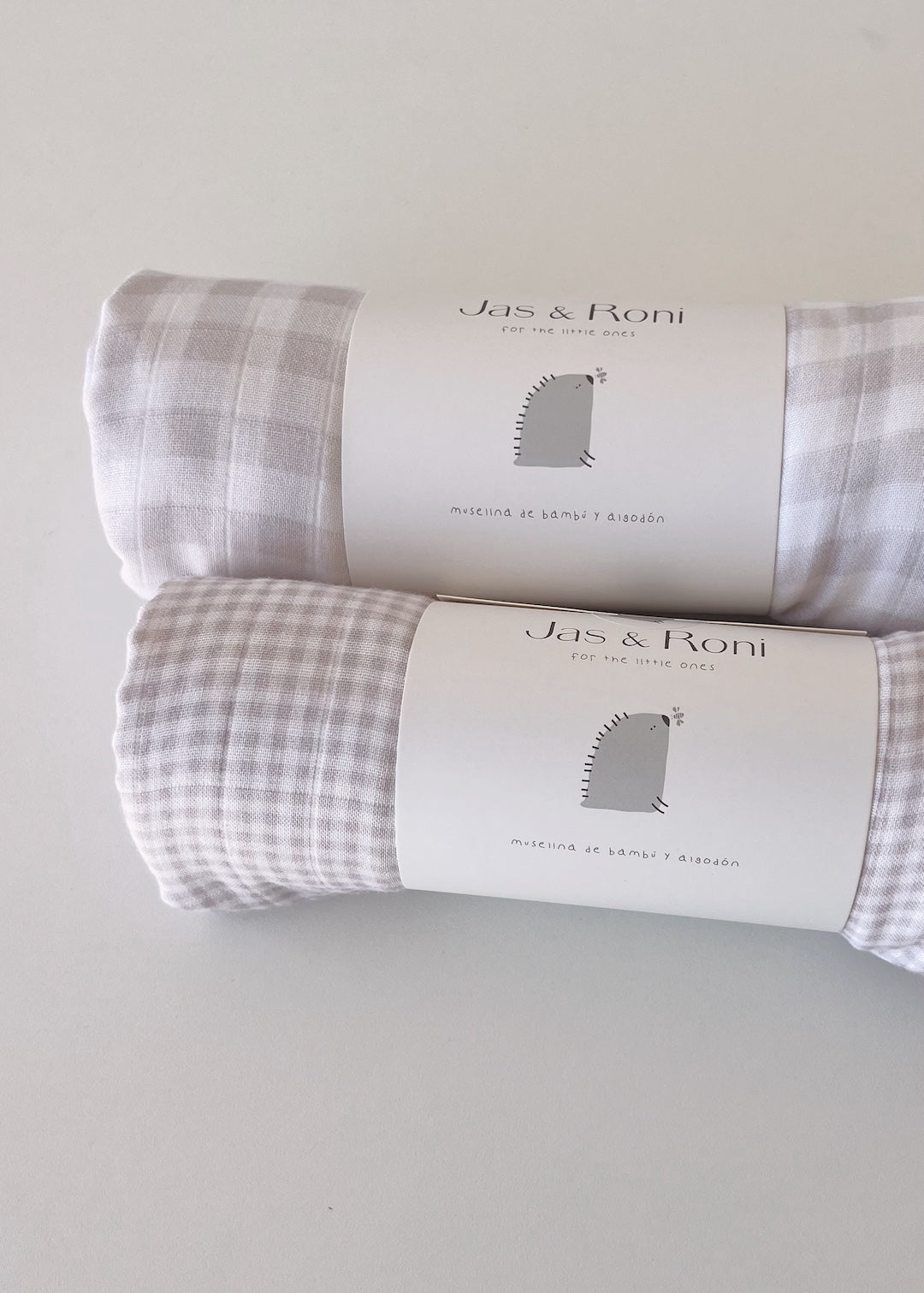 Fotos de dos muselinas enrolladas a cuadros sobre fondo blanco