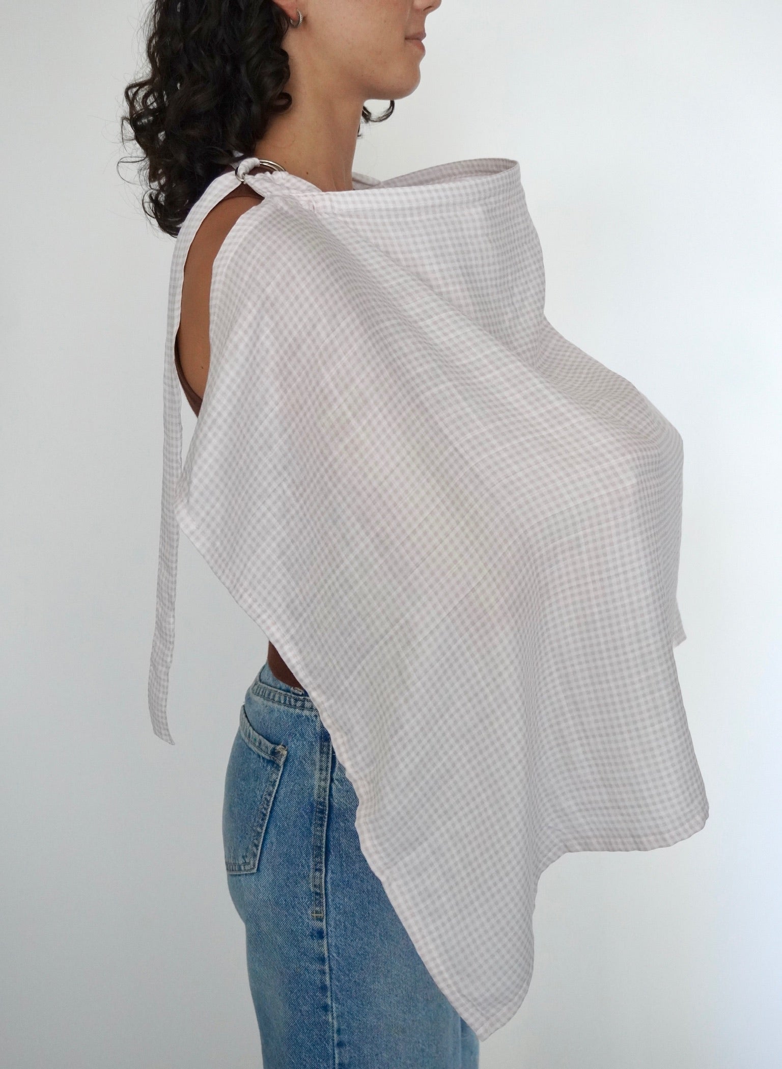 Mujer cubierta con una manta de lactancia a cuadros rosas