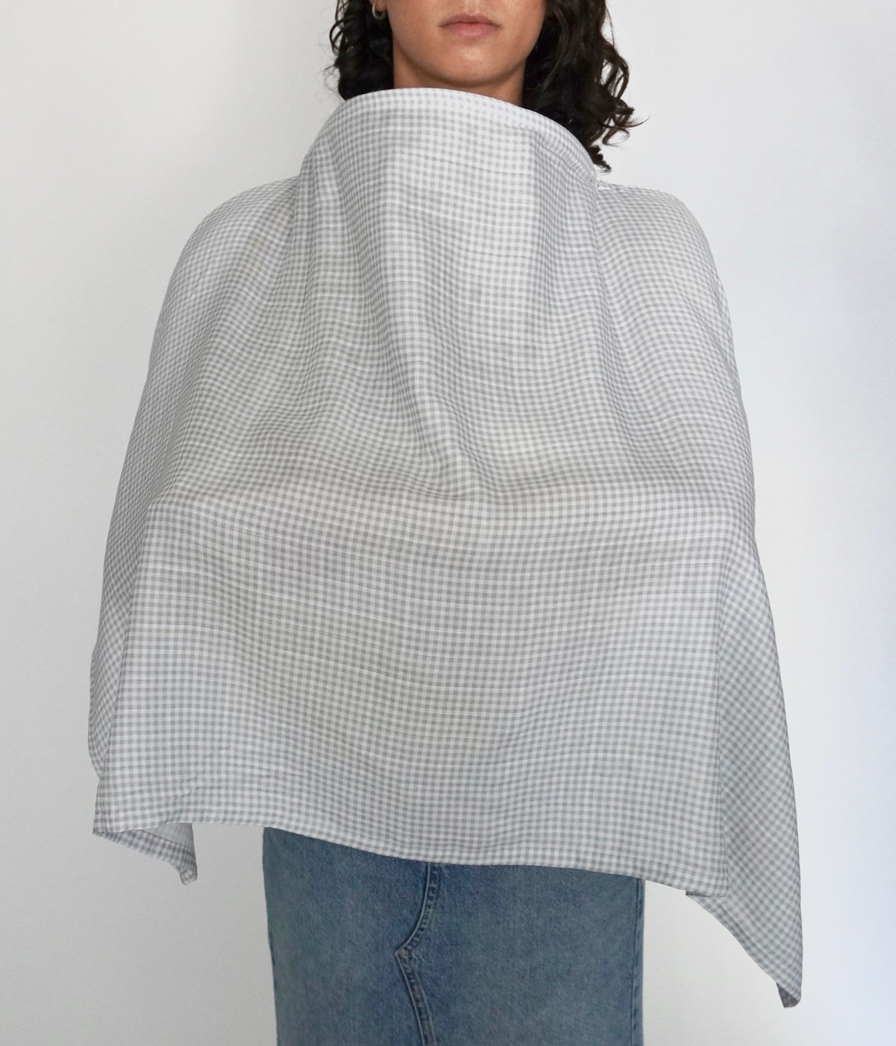 Mujer cubierta con una manta de lactancia a cuadros gris