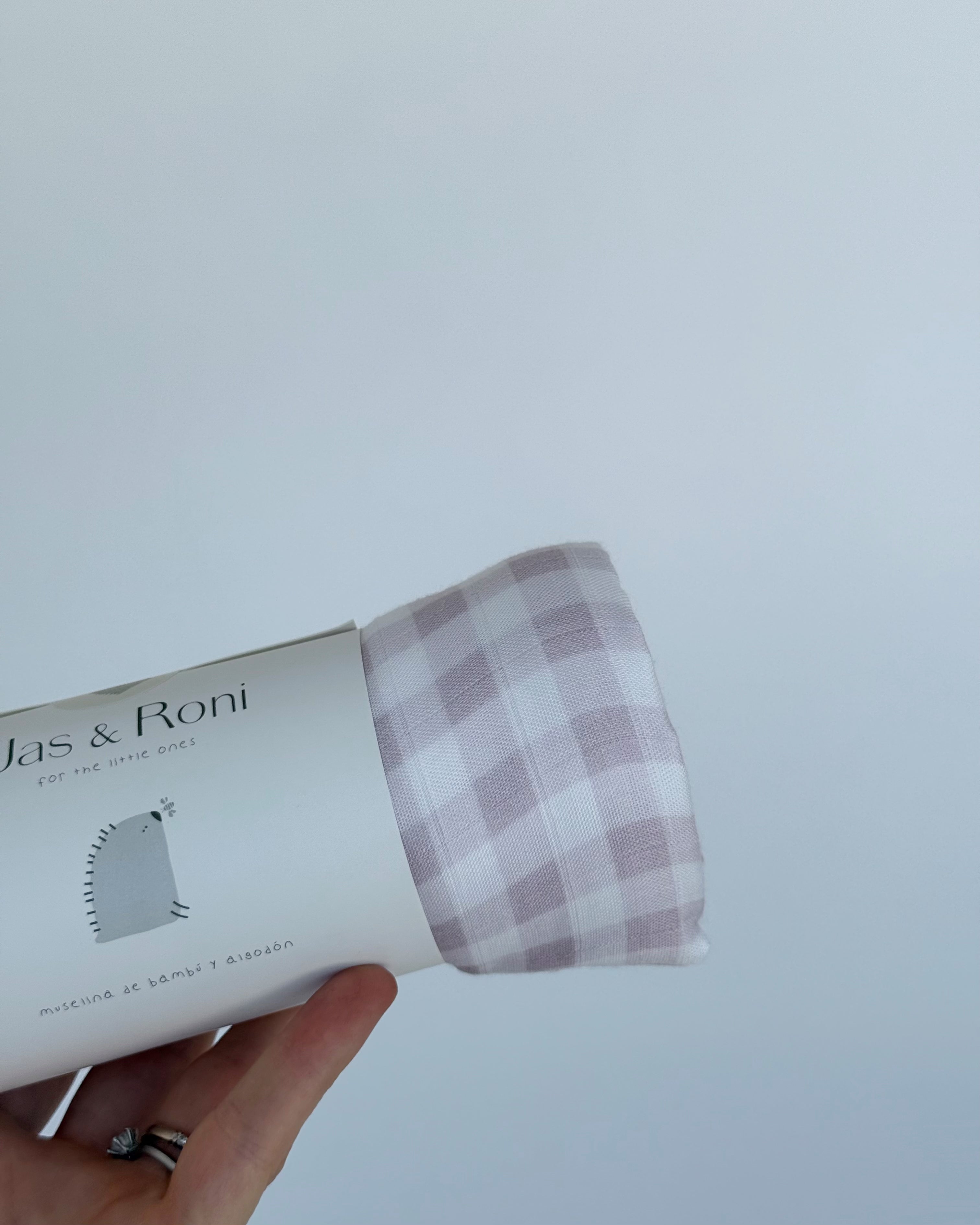 Mano sosteniendo una muselina enrollada de cuadros rosas