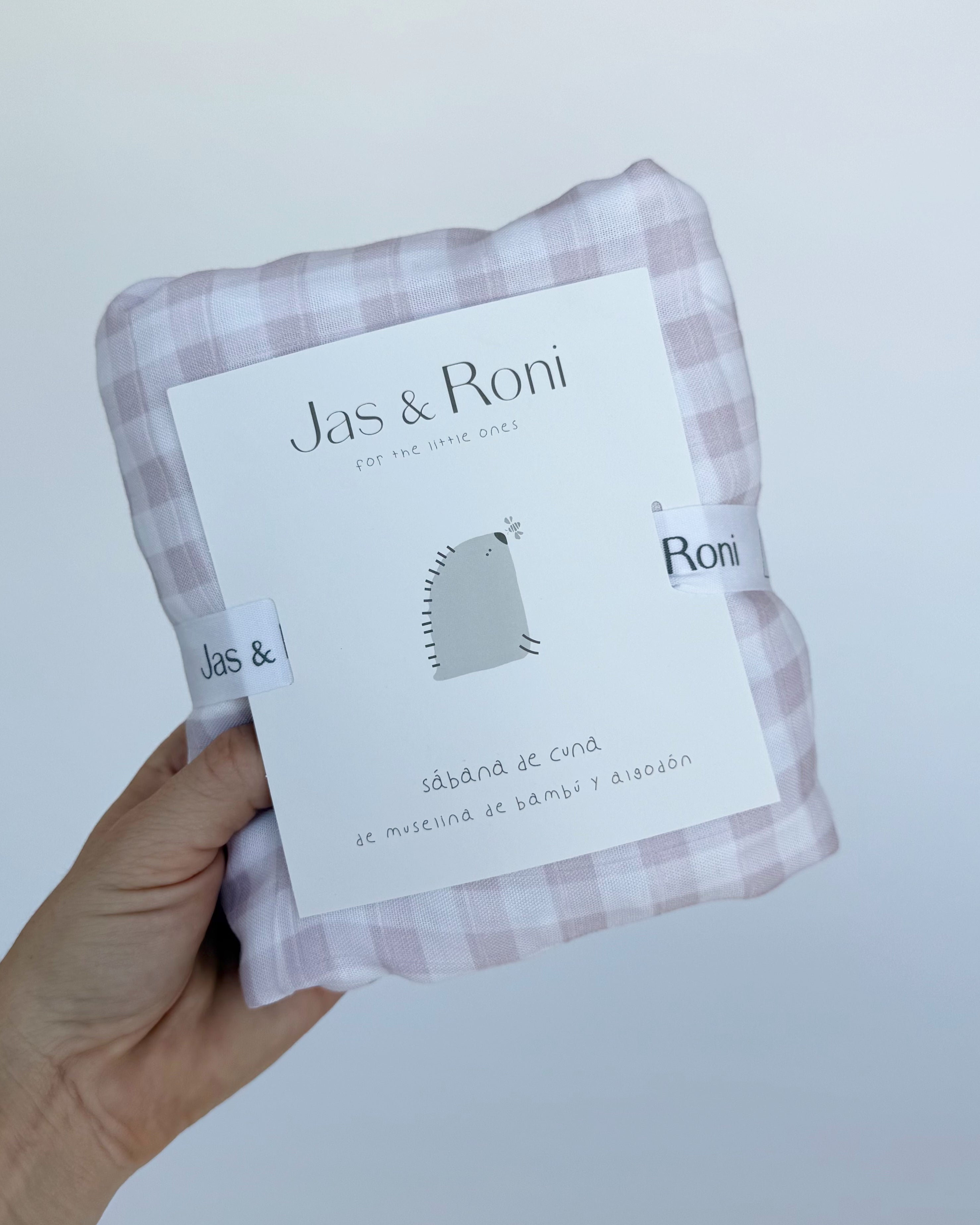 Sabana de muselina doblada de cuadros color rosa con etiqueta