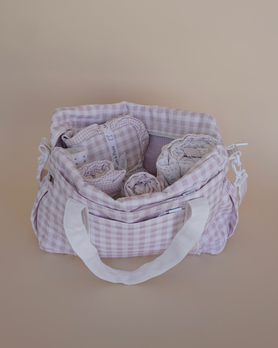 Pañalera abierta de tela estampada en cuadros rosas en fondo crema