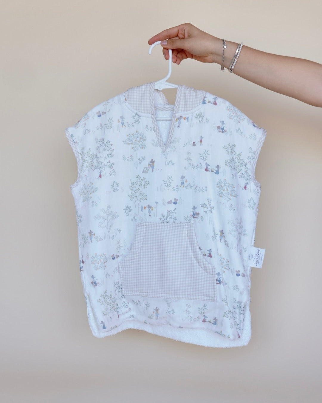 Poncho de toalla y muselina en gancho sostenido por una mano estampado en ratones